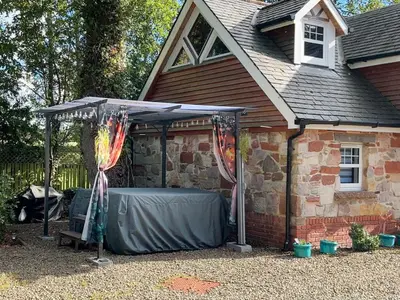 a gazebo in front of a brick house at Lily Wood Cottage outside Hurlford in Hurlford