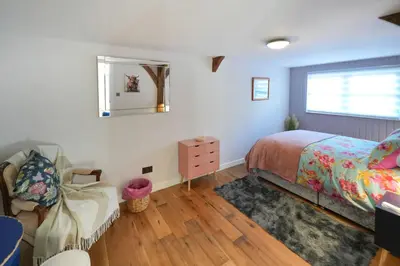 a bedroom with a bed and a dresser and a mirror at Lily Wood Cottage outside Hurlford in Hurlford