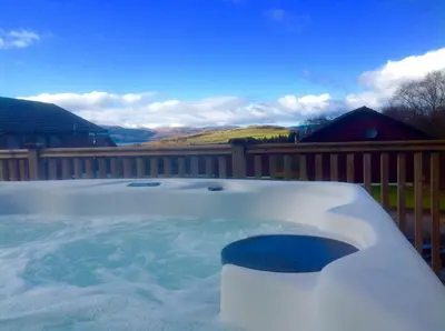 a hot tub in a yard with a wooden fence at Skye Lodge in Tighnabruaich