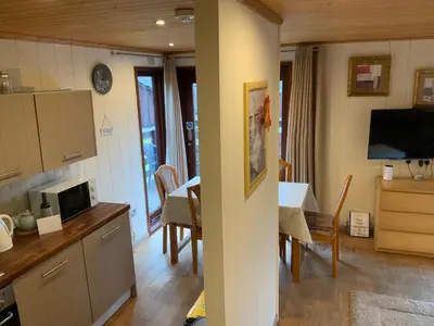 a kitchen and dining room with a table and a television at Skye Lodge in Tighnabruaich