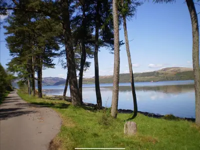 a path next to a body of water with trees at Skye Lodge in Tighnabruaich