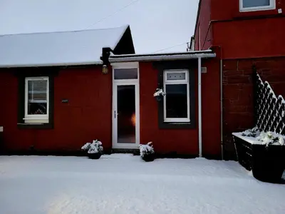 a red house with snow in front of it at Ta'Pinu House and Spa in Horse Isle