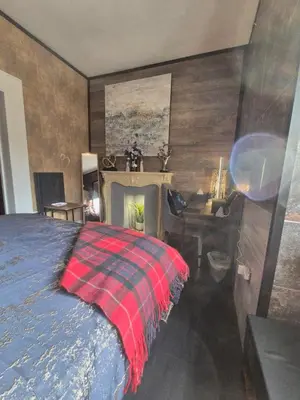 a bedroom with a bed and a desk and a fireplace at Ta'Pinu House and Spa in Horse Isle