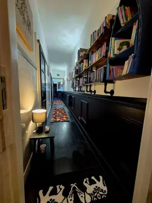 a long hallway with bookshelves and a hallway with a rug at Ta'Pinu House and Spa in Horse Isle