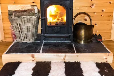 a stove with a fire in a room at Woodcock Lodge in Kilmichael Glassary