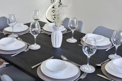 a black table with white plates and wine glasses at Vacant Nests Dunfermline WiFi Priv-Parking in Fife
