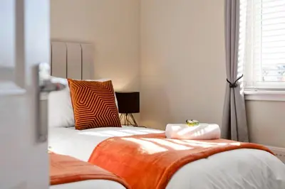 a bedroom with two beds with orange and white sheets at Vacant Nests Dunfermline WiFi Priv-Parking in Fife