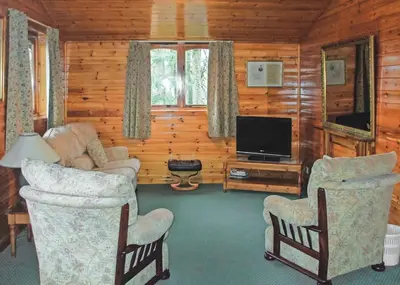 a living room with chairs and a flat screen tv at Hideaway Lodges in Boʼness