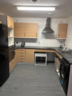 a kitchen with wooden cabinets and a black appliance at One Bedroom Apartment in Greenwich Peninsula in Moffat