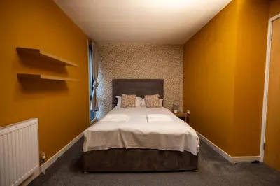 a bedroom with yellow walls and a bed in it at Muirhouse 2BR Apartment with Free Parking in Glasgow
