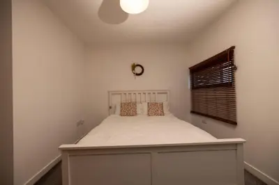 a bedroom with a white bed with a window at Muirhouse 2BR Apartment with Free Parking in Glasgow
