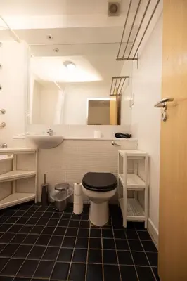 a bathroom with a toilet with a sink and a mirror at Muirhouse 2BR Apartment with Free Parking in Glasgow