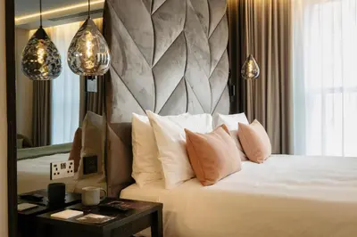 a bedroom with a bed with pillows and a mirror at The Wellington Glasgow by Adina in Glasgow