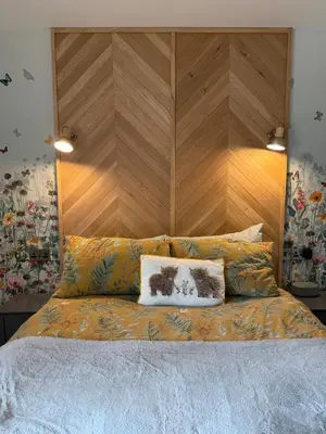 a bed with a wooden headboard and two pillows at Distillers Cottage, Peaceful rural retreat in Lanarkshire, onsite craft distillery, hot tub, bbq hut, central for exploring Scotland in Forth