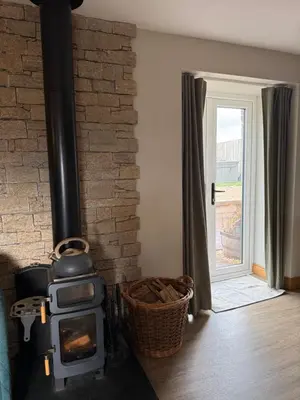 a wood stove in a room with a door at Distillers Cottage, Peaceful rural retreat in Lanarkshire, onsite craft distillery, hot tub, bbq hut, central for exploring Scotland in Forth