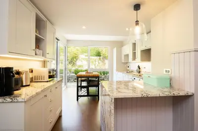 a kitchen with white cabinets and a marble counter top at Stables Cottage in Dunira