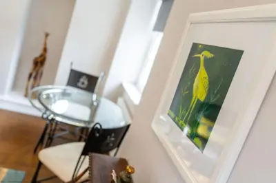 a dining room with a framed picture of a yellow bird at Stables Cottage in Dunira