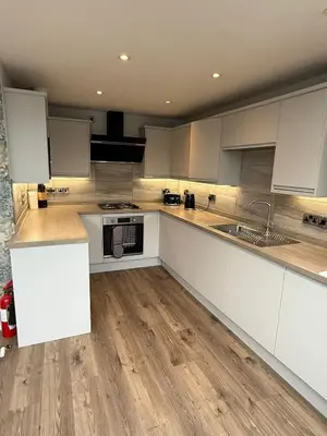 a kitchen with white cabinets and a wooden floor at Luxury townhouse in Stirling in Stirling