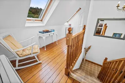a room with a staircase with a chair and a mirror at Stunning 2 Bed Riverside Cottage near Oban in Oban