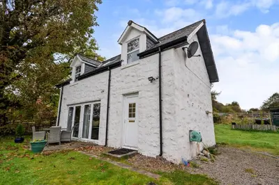 a small white building with a white door at Stunning 2 Bed Riverside Cottage near Oban in Oban