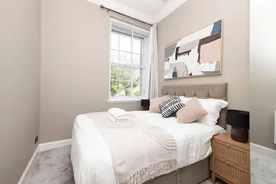 a bedroom with a bed with white sheets and a window at 1 bed in heart of Old Town with Castle Views in Edinburgh