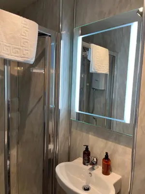 a bathroom with a sink and a shower and a mirror at Ravenswood Guest House in Stirling