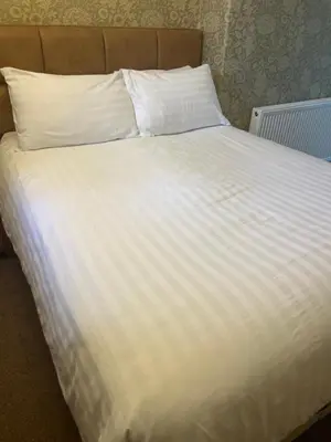 a large white bed with white sheets and pillows at Ravenswood Guest House in Stirling