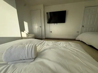 a white bed with two pillows on it in a bedroom at 4BR Home near Airport & City Centre Free Parking in Edinburgh