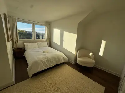 a bedroom with a bed and a chair and a window at 4BR Home near Airport & City Centre Free Parking in Edinburgh