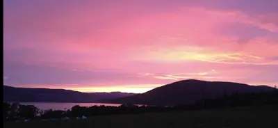 a sunset over a body of water with mountains at Sunset View in Innellan