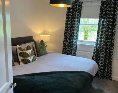 a bedroom with a bed with a window and a bedskirtspectspectspectspects at Fifty Five on Gilmour Street in Eaglesham
