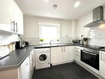 a white kitchen with a washer and dryer in it at Fifty Five on Gilmour Street in Eaglesham