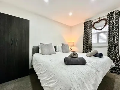 a bedroom with a large white bed with a black cabinet at Fifty Five on Gilmour Street in Eaglesham