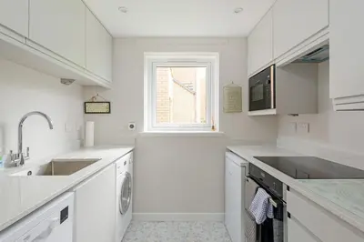 a white kitchen with a sink and a dishwasher at Lovely Edinburgh Home - Craighouse Gardens in Edinburgh