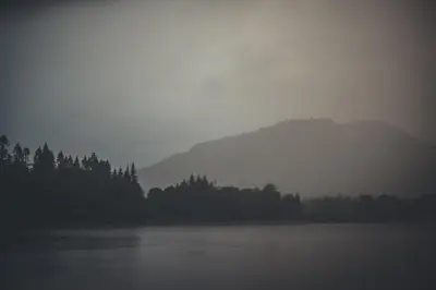 a misty view of a mountain and a lake at NICHT' Apartments Inveraray Town Centre in Inveraray