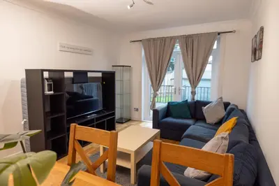 a living room with a blue couch and a tv at Knightswood in Knightswood