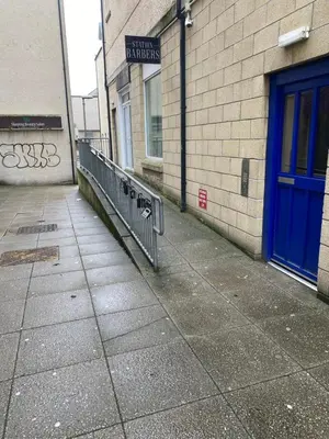 a sidewalk next to a building with a blue door at Number one faraline in Moffat