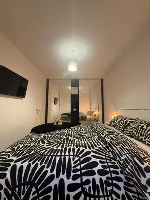 a bedroom with a black and white bed and a tv at Premium Village Stay near Train & Loch in Lochwinnoch