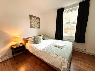 a bedroom with a bed with a lamp and a window at Clapham Road Apartment in Moffat