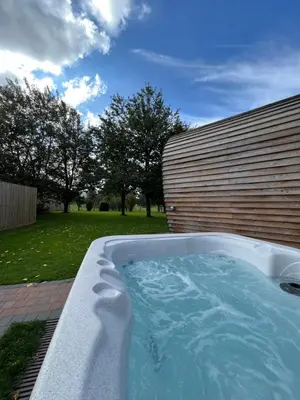 a jacuzzi tub in a yard next to a building at Whitemoss Lodge in Dunning