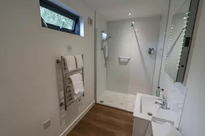 a white bathroom with a shower and a sink at Whitemoss Lodge in Dunning