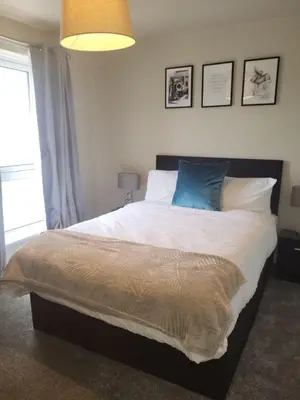 a bedroom with a large bed with a blue pillow at The MacIntyre - Coorie Doon Stays in Kilmarnock