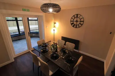 a dining room with a table and chairs and a clock at Edinburgh West Luxury 5 Bedroom Home in Edinburgh