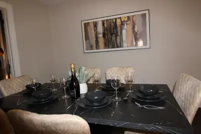 a black table with glasses and a bottle of wine at Edinburgh West Luxury 5 Bedroom Home in Edinburgh