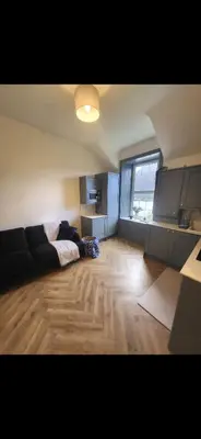 a living room with a black couch and a large window at Kirkgate 2 bed - Coorie Doon Stays in Irvine
