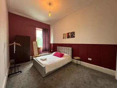 a bedroom with a bed with two pink pillows on it at Victorian 5 Bedroom House Free Parking SSE Central in Glasgow