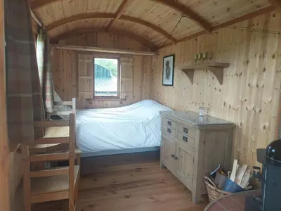 a bedroom with a bed and a staircase in a cabin at Shepherd's Hut Harmony at A Therapeutic Space in Moniaive