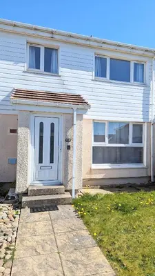 a white house with a blue door in front of it at Fairway house in Campbeltown