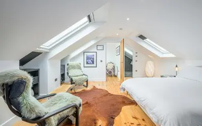 a bedroom with a large bed and two chairs at Blà Bheinn by Birch Stays in Dunollie