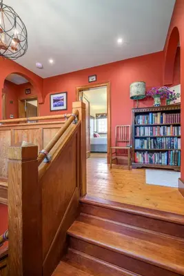 a library with a staircase and a book shelf with books at Blà Bheinn by Birch Stays in Dunollie